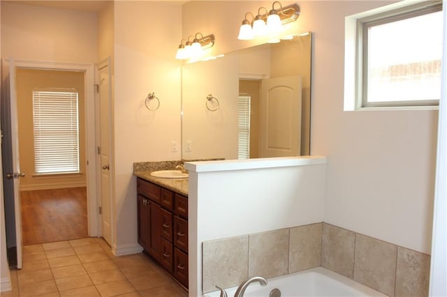 full bathroom with vanity, a garden tub, tile patterned flooring, and baseboards