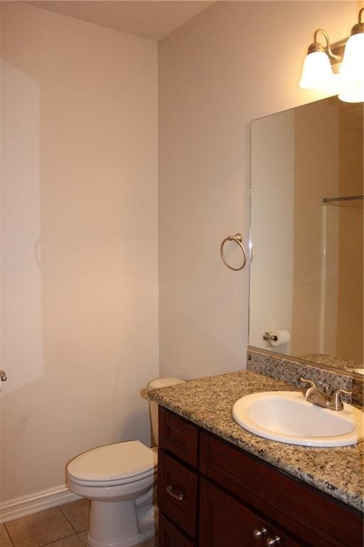bathroom with vanity, toilet, tile patterned flooring, and baseboards