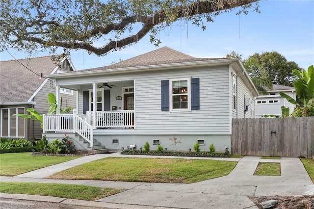 bungalow with a ceiling fan, a porch, fence, a front yard, and a shingled roof