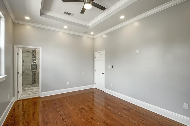 spare room featuring ceiling fan, a tray ceiling, crown molding, and dark wood-type flooring