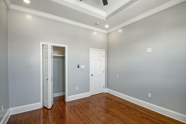 unfurnished bedroom featuring ceiling fan, ornamental molding, dark wood-type flooring, and a high ceiling