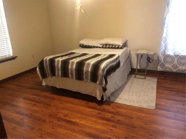 bedroom with multiple windows and dark wood-type flooring