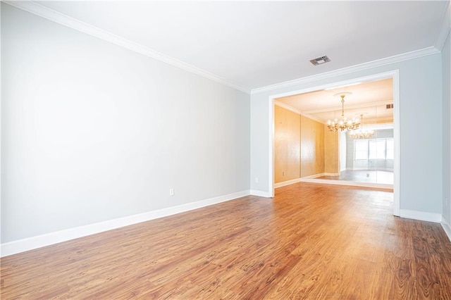 empty room with an inviting chandelier, ornamental molding, and hardwood / wood-style floors