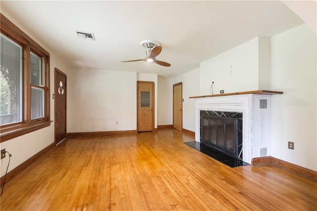 unfurnished living room with ceiling fan, light wood-type flooring, and a high end fireplace