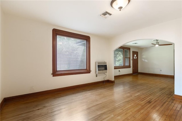 unfurnished living room with heating unit, ceiling fan, and light wood-type flooring