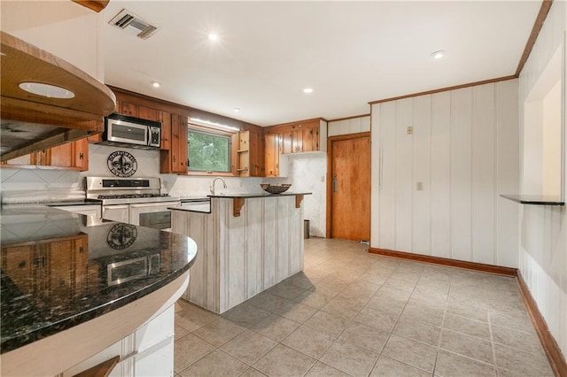 kitchen featuring sink, light tile patterned floors, tasteful backsplash, stainless steel appliances, and a breakfast bar area