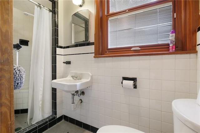 bathroom featuring tile walls, a shower with curtain, sink, and toilet