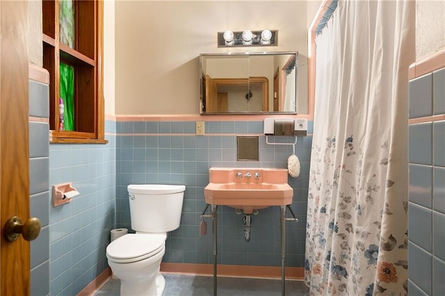 bathroom featuring tile walls, sink, curtained shower, and toilet