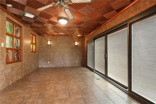 spare room featuring ceiling fan, light tile patterned flooring, and tile walls