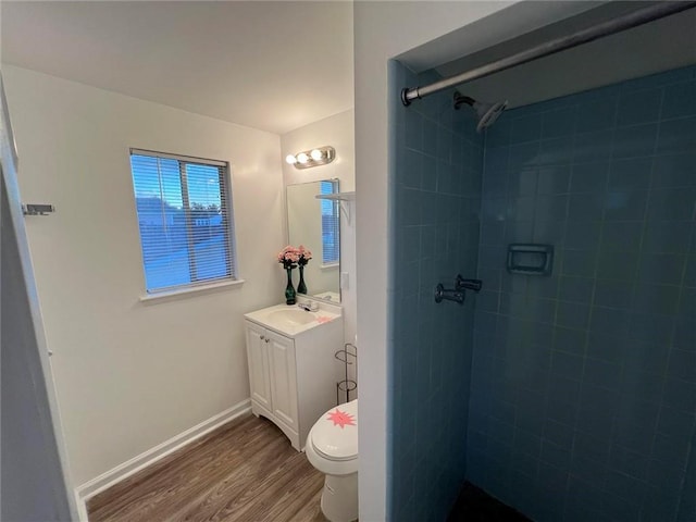 bathroom featuring a tile shower, vanity, toilet, and hardwood / wood-style flooring