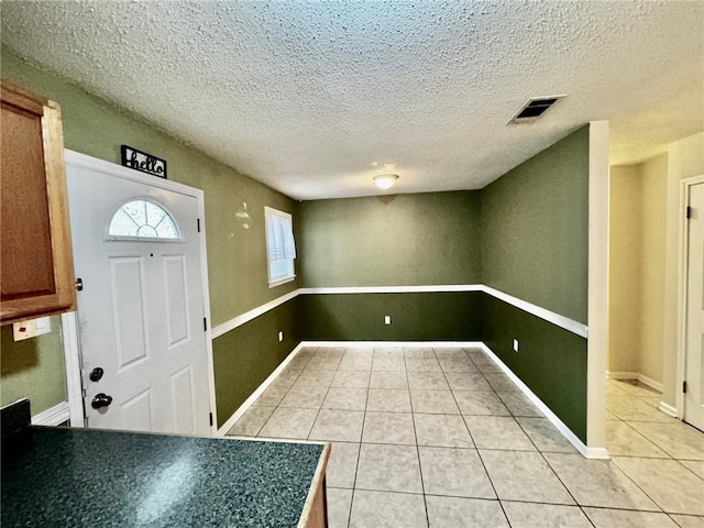 foyer entrance featuring a textured ceiling and light tile patterned floors