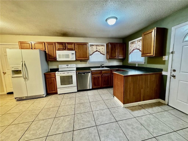 kitchen featuring light tile patterned flooring, a textured ceiling, white appliances, and sink