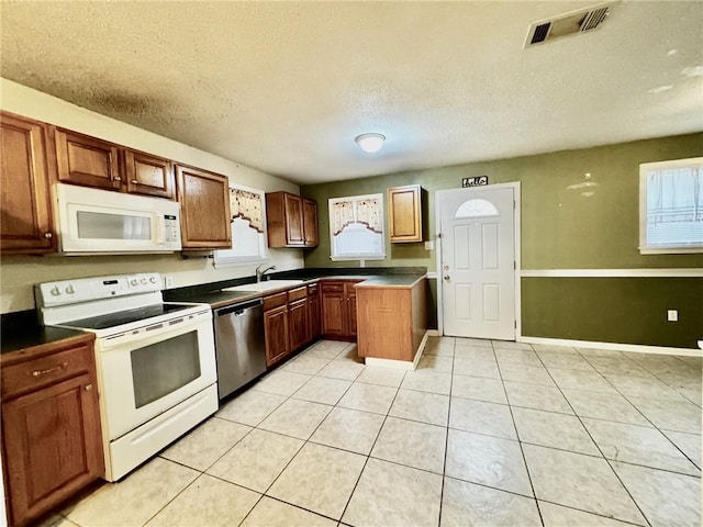 kitchen with white appliances, a textured ceiling, light tile patterned floors, and sink