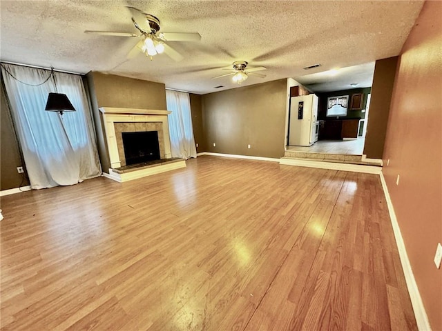 unfurnished living room featuring a textured ceiling, a fireplace, hardwood / wood-style flooring, and ceiling fan