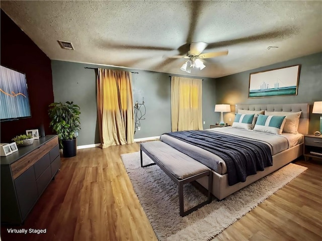 bedroom with hardwood / wood-style floors, a textured ceiling, and ceiling fan