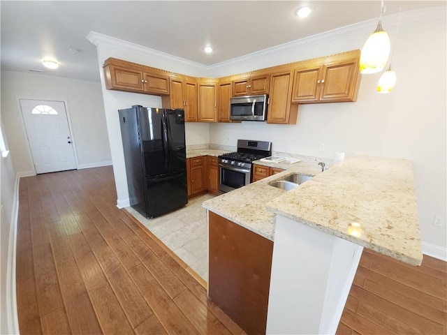 kitchen featuring pendant lighting, kitchen peninsula, appliances with stainless steel finishes, and light hardwood / wood-style flooring