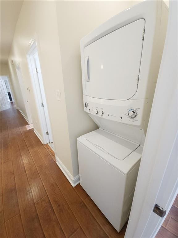 laundry area with dark hardwood / wood-style floors and stacked washer and dryer