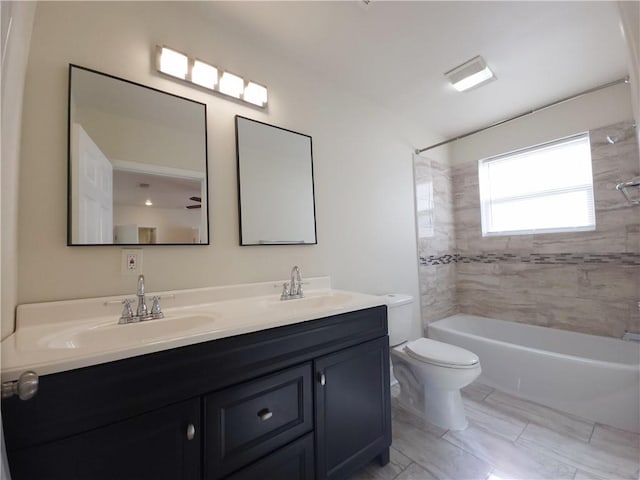 full bathroom with vanity, tiled shower / bath combo, and toilet