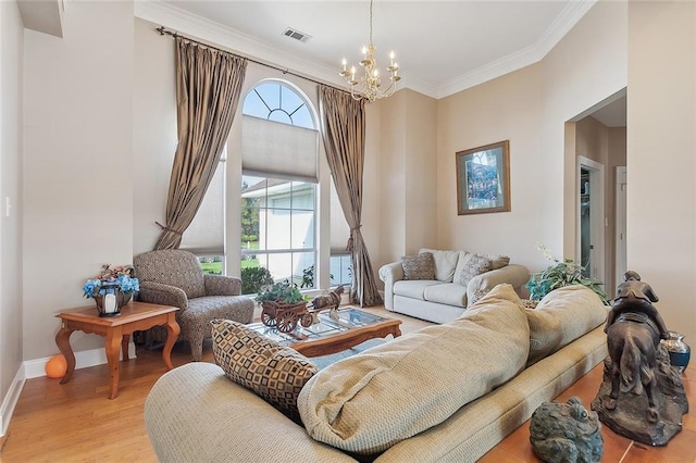 living room featuring ornamental molding, light hardwood / wood-style floors, and an inviting chandelier