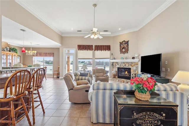 tiled living room featuring ceiling fan with notable chandelier, a stone fireplace, and crown molding