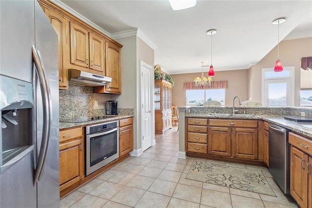 kitchen featuring appliances with stainless steel finishes, light stone counters, sink, decorative light fixtures, and a chandelier