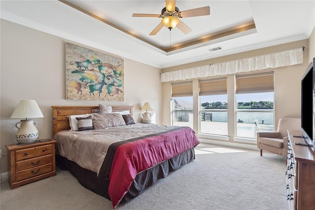 bedroom with a raised ceiling, ceiling fan, and light carpet