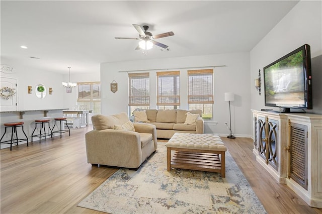 living room featuring ceiling fan with notable chandelier and light hardwood / wood-style floors