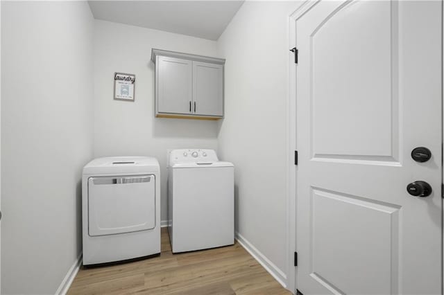 clothes washing area with light hardwood / wood-style flooring, washing machine and clothes dryer, and cabinets