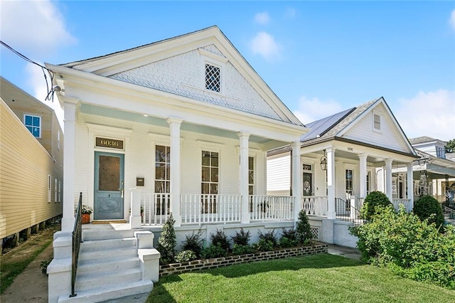 greek revival inspired property featuring a front lawn and covered porch