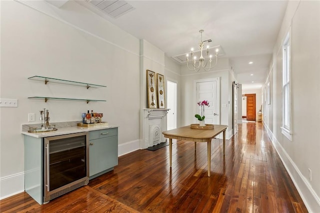 corridor with an inviting chandelier, wine cooler, and dark hardwood / wood-style flooring