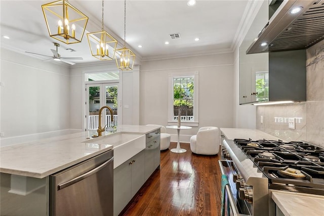 kitchen with sink, decorative light fixtures, wall chimney exhaust hood, stainless steel appliances, and dark hardwood / wood-style flooring