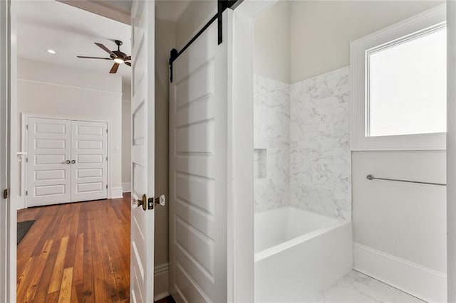 bathroom with tiled shower / bath combo, ceiling fan, and hardwood / wood-style flooring