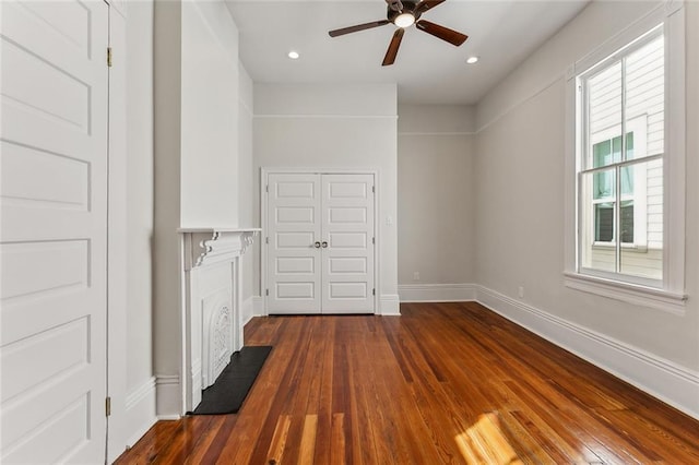 unfurnished living room with ceiling fan and dark wood-type flooring