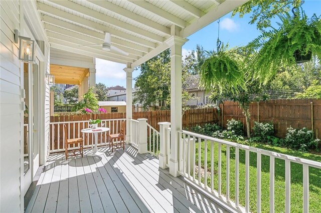 wooden deck featuring a lawn and ceiling fan