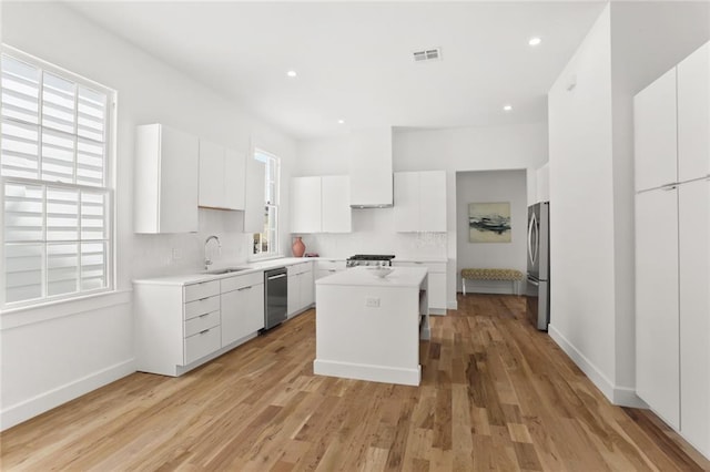 kitchen featuring light hardwood / wood-style flooring, white cabinetry, appliances with stainless steel finishes, and a kitchen island