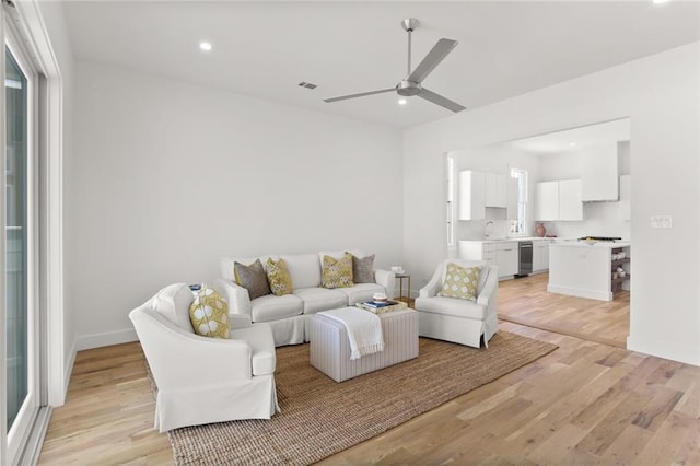 living room featuring ceiling fan, sink, and light hardwood / wood-style floors