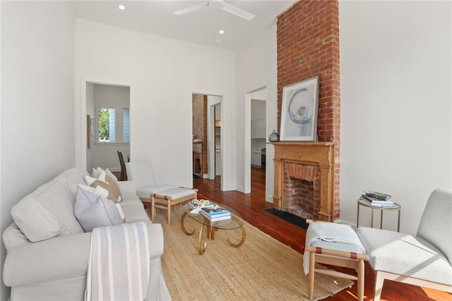 living room featuring hardwood / wood-style floors, ceiling fan, and a brick fireplace