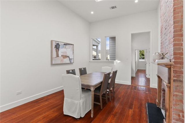 dining space with dark hardwood / wood-style floors and a brick fireplace