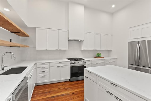 kitchen with sink, white cabinetry, light hardwood / wood-style flooring, backsplash, and appliances with stainless steel finishes