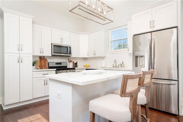 kitchen featuring pendant lighting, a center island, dark hardwood / wood-style floors, white cabinets, and stainless steel appliances