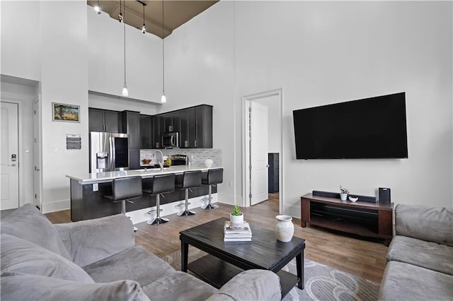 living room featuring sink, a high ceiling, and dark hardwood / wood-style floors