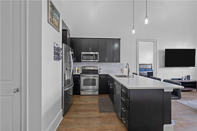 kitchen with hanging light fixtures, kitchen peninsula, sink, a breakfast bar, and appliances with stainless steel finishes