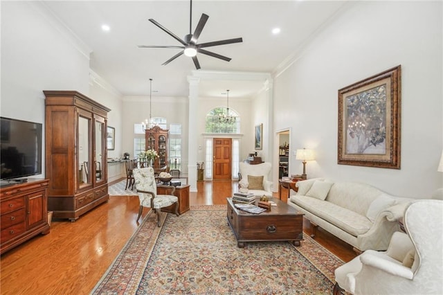 living room featuring ceiling fan with notable chandelier, light hardwood / wood-style flooring, and ornamental molding