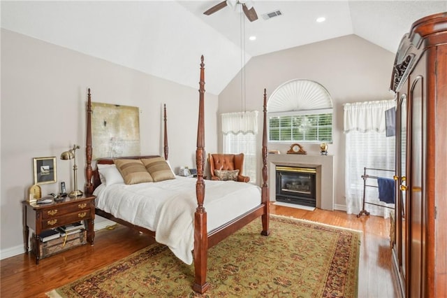 bedroom with ceiling fan, hardwood / wood-style flooring, and high vaulted ceiling