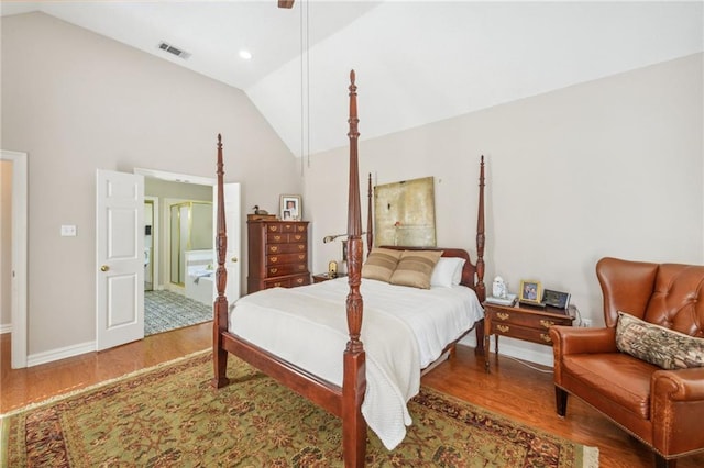 bedroom featuring lofted ceiling, ensuite bathroom, and hardwood / wood-style flooring