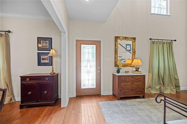 foyer entrance with ornamental molding and light hardwood / wood-style floors