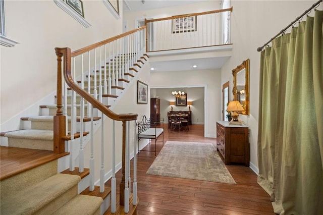 entryway featuring a towering ceiling, an inviting chandelier, and dark hardwood / wood-style floors