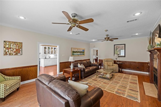 living room featuring light hardwood / wood-style floors, wood walls, and ceiling fan