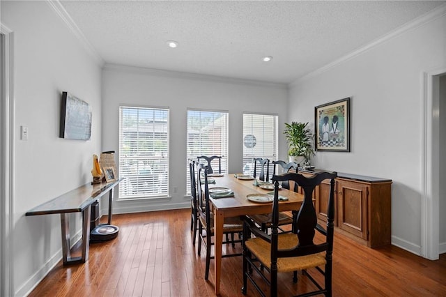 dining room featuring a textured ceiling, ornamental molding, and hardwood / wood-style floors