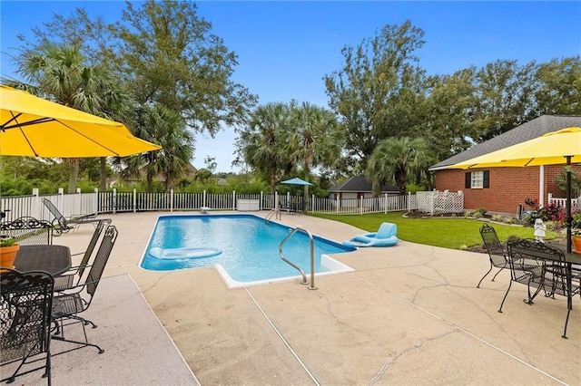 view of pool with a diving board, a lawn, and a patio